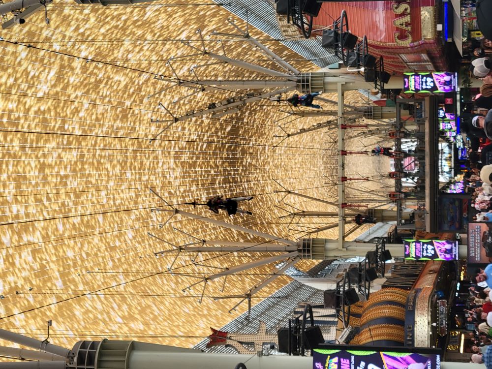 Zipliners soaring from SlotZilla over the Fremont Street Experience canopy in Las Vegas
