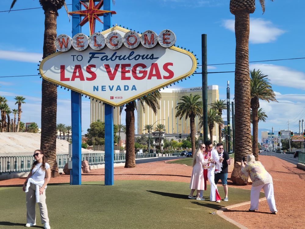 Elvis impersonator posing beside the Welcome to Fabulous Las Vegas sign