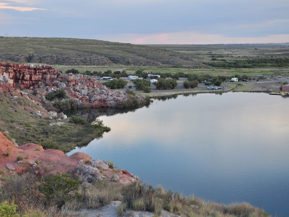 Spring-fed sinkhole lake surrounded by red bluffs and desert vegetation at Bottomless Lakes State Park, New Mexico