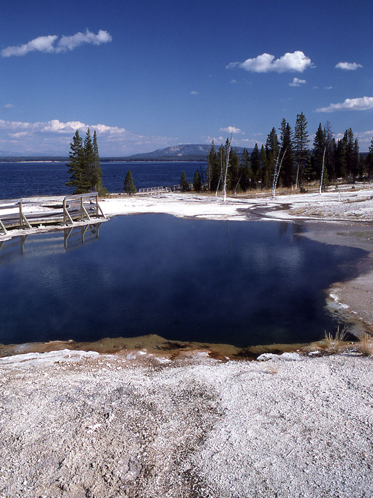 Black Pool hot spring with Yellowstone Lake in the background