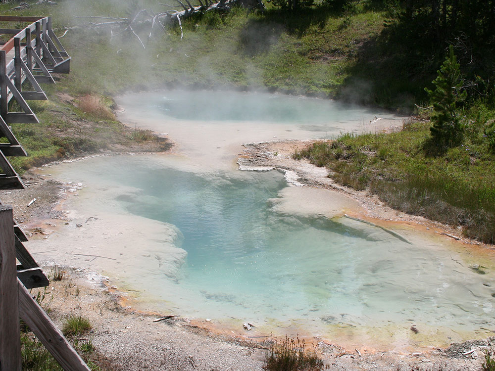 Blue hot spring pool steaming at West Thumb Geyser Basin